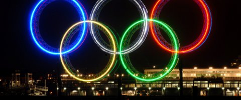 File photo of Olympic Rings lit at night, adapted from state.gov image