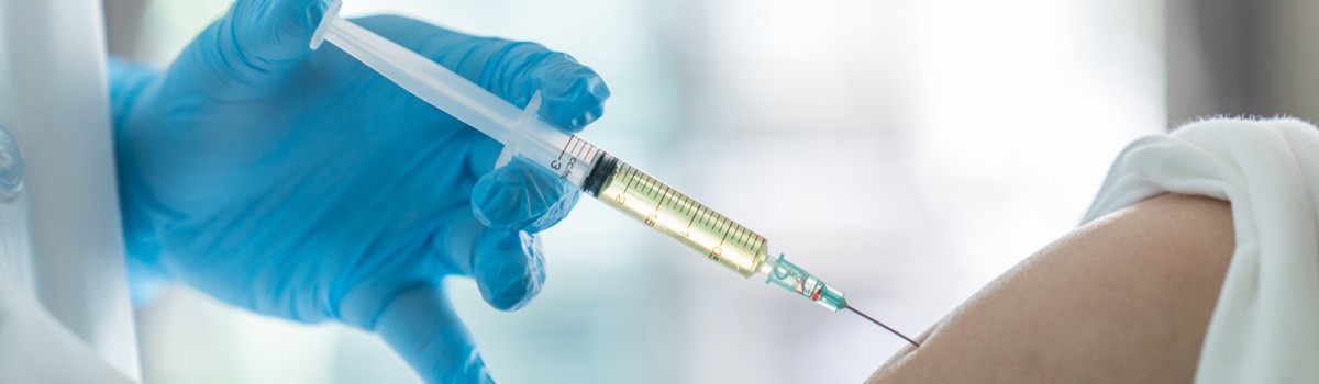 Gloved Hand Injecting Syringe Into Arm, file photo adapted from image at NIH.gov